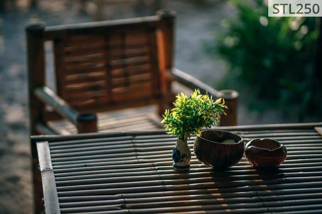 Serene bamboo seating arrangement with vase and greenery in a Thai garden setting.