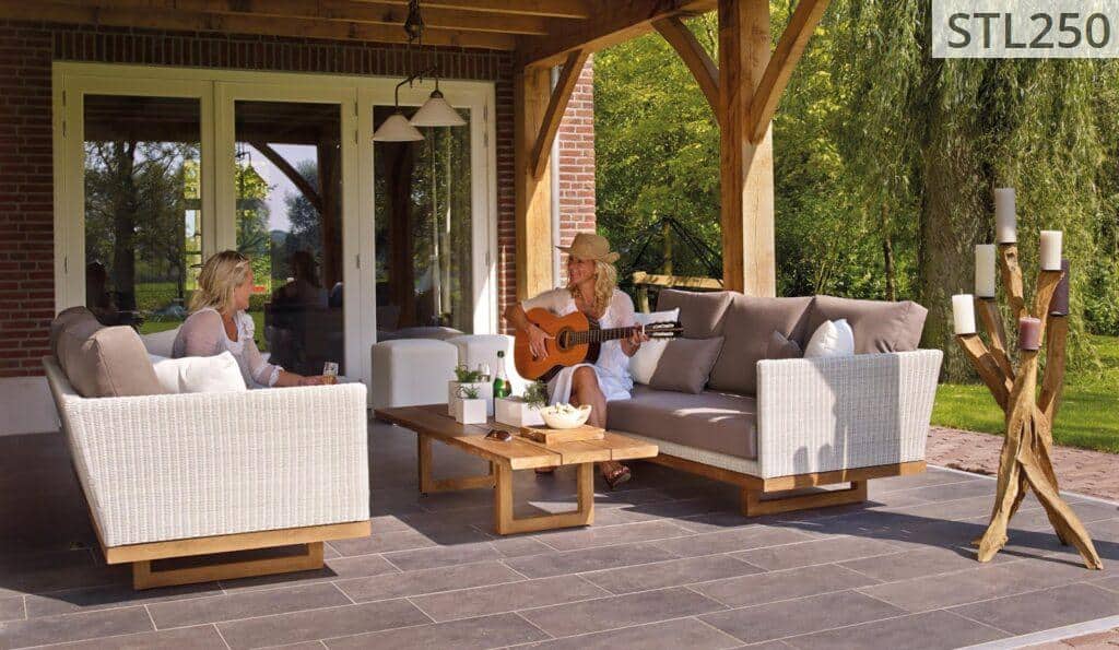 Two women enjoying a serene patio scene with a guitar and candles, surrounded by greenery.
