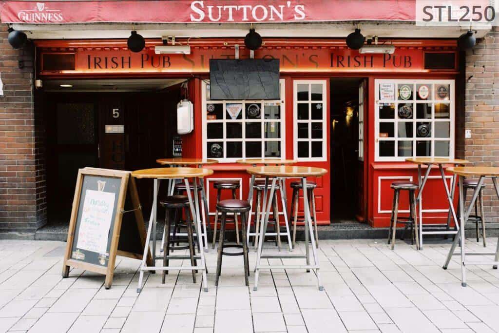 Cozy Irish pub exterior with vibrant red facade and inviting seating. Perfect for urban exploration.