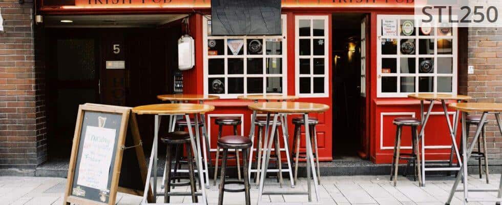 Cozy Irish pub exterior with vibrant red facade and inviting seating. Perfect for urban exploration.